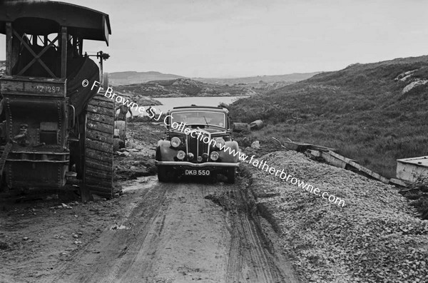 CAR PASSING STEAMROLLER ON NARROW ROAD